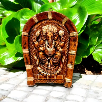 Side angle view of handmade terracotta Lord Ganesha wall hanging on rice plate highlighting relief art details